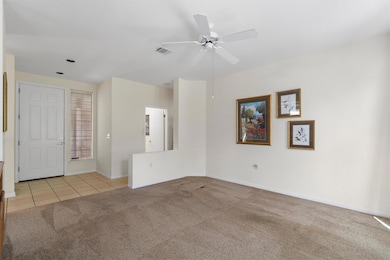 Spare room featuring light colored carpet, light tile patterned floors, and ceiling fan