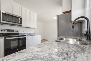 Kitchen with white cabinetry, stainless steel appliances, and hardwood / wood-style flooring