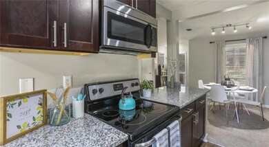 Kitchen with dark brown cabinets, light stone counters, rail lighting, and electric stove