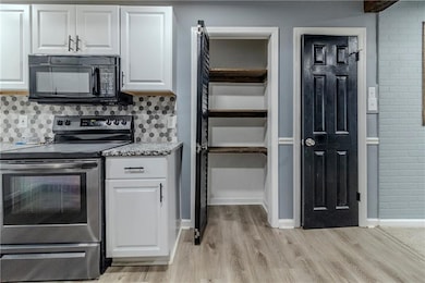 Kitchen featuring white cabinetry, stainless steel