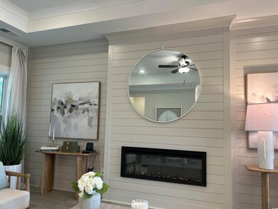 Living area featuring ceiling fan, wood walls, a glass covered fireplace, and wood finished floors