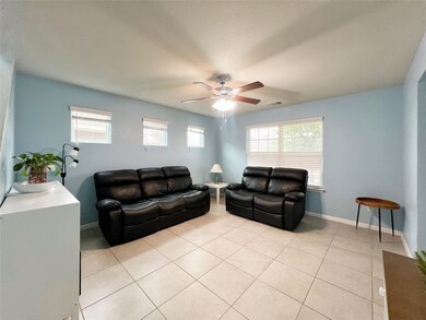 Living room featuring a ceiling fan, light tile p