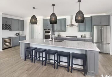 Kitchen featuring appliances with stainless steel finishes, wall chimney exhaust hood, a sink, beverage cooler, and a kitchen breakfast bar