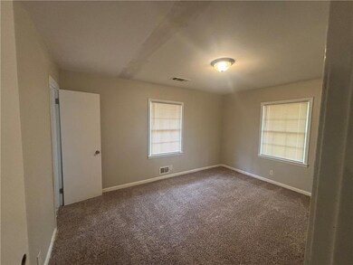 Spare room featuring dark carpet, baseboards, and 