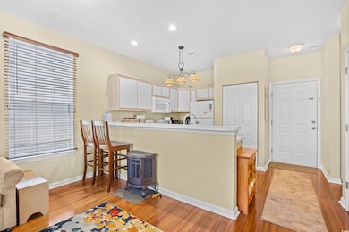 Kitchen featuring white appliances, light wood-style flooring, a peninsula, light countertops, and recessed lighting