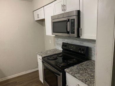 Kitchen with black electric range oven, stainless steel microwave, and white cabinetry
