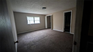 Unfurnished room with baseboards, dark carpet, and