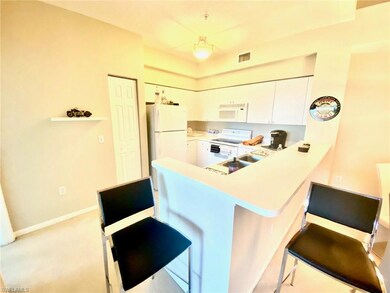 Kitchen featuring white appliances, a breakfast bar area, light countertops, white cabinets, and a peninsula