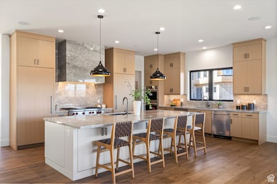 Kitchen with tasteful backsplash, light brown cabinetry, light stone countertops, decorative light fixtures, and recessed lighting