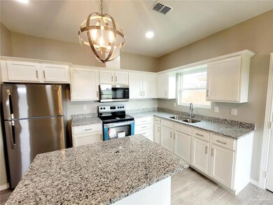 Kitchen with appliances with stainless steel finishes, white cabinetry, a chandelier, light stone countertops, and recessed lighting