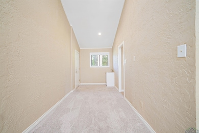Hall featuring a textured wall, carpet floors, and baseboards
