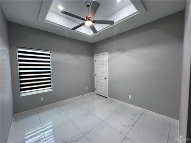 Empty room with ceiling fan, a tray ceiling, and light marble finish floors