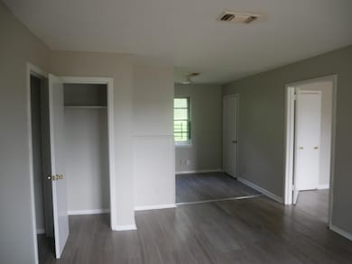 Unfurnished bedroom with wood finished floors, baseboards, and a closet