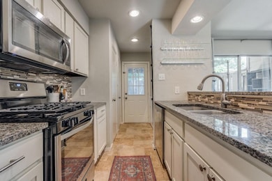 Kitchen with light stone counters, sink, white cab