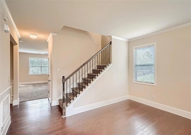 Stairs featuring ornamental molding, hardwood / wood-style floors, and baseboards