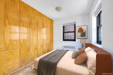 Bedroom with radiator heating unit, multiple windows, and wood finished floors