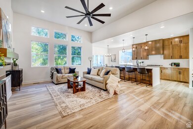 Living area with recessed lighting, light wood finished floors, ceiling fan, and a chandelier