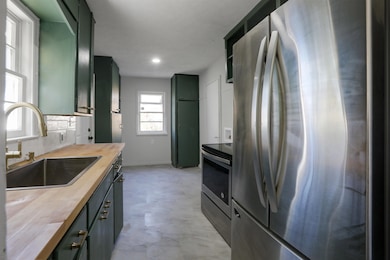 Kitchen featuring green cabinetry, appliances with stainless steel finishes, and butcher block counters