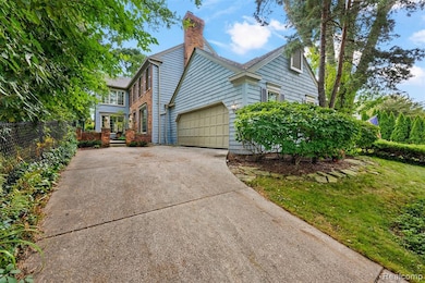 View of front of property featuring driveway, a chimney, and a garage