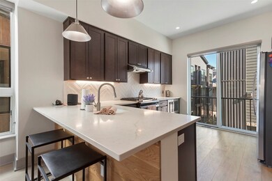 Kitchen featuring decorative backsplash, a kitchen breakfast bar, a peninsula, appliances with stainless steel finishes, and light wood-style flooring
