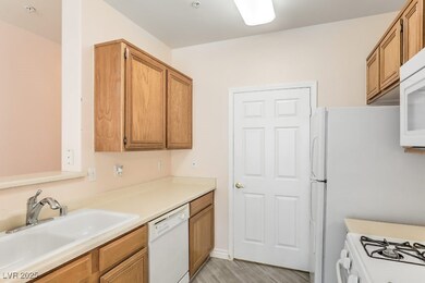 Kitchen with white appliances, light countertops, brown cabinets, and light wood-type flooring
