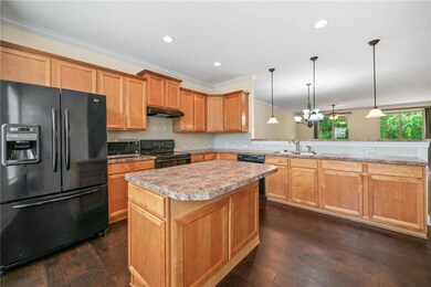 Kitchen with black appliances, under cabinet range hood, a sink, a peninsula, and light countertops