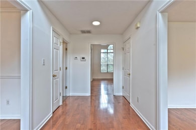 Hall with baseboards, visible vents, and wood fini