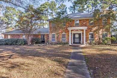 Georgian-style home featuring a front lawn and brick siding