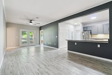 Unfurnished living room with ceiling fan, ornamental molding, and light wood plank tile floors