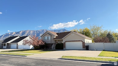 View of front of property with a mountain view, brick siding, a garage, and concrete driveway