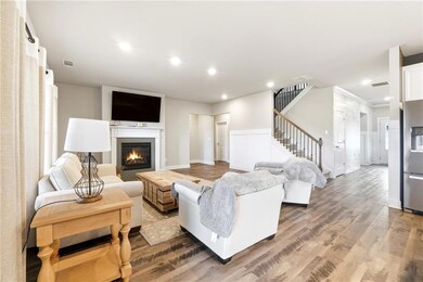 Living room featuring wood finished floors, stairway, a glass covered fireplace, recessed lighting, and a wainscoted wall