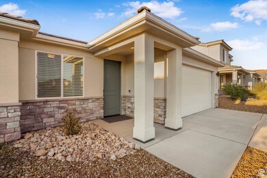 View of exterior entry featuring stucco siding, stone siding, an attached garage, and concrete driveway