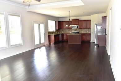 Kitchen with appliances with stainless steel finishes, a kitchen island, decorative backsplash, light countertops, and decorative light fixtures
