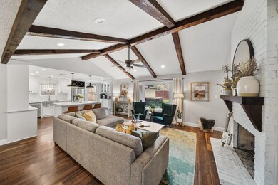 A wood-beamed cathedral ceiling sets the stage in this gorgeous family room with recessed lighting, ceiling fan with light fixture, large windows overlooking the backyard & laminate hardwood flooring.