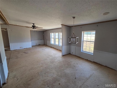 Unfurnished living room with crown molding, a chandelier, a ceiling fan, carpet, and a textured ceiling