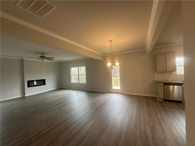 Unfurnished living room with ceiling fan with notable chandelier, a glass covered fireplace, visible vents, baseboards, and dark wood finished floors