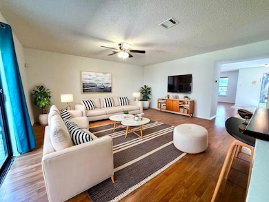 Living area with wood finished floors, a textured ceiling, and ceiling fan