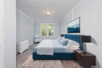 Bedroom featuring ornamental molding, radiator, wood finished floors, and an ornate ceiling