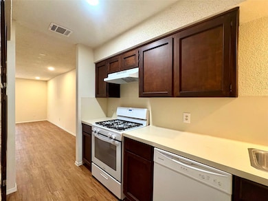 Kitchen featuring dark brown cabinets, visible ve