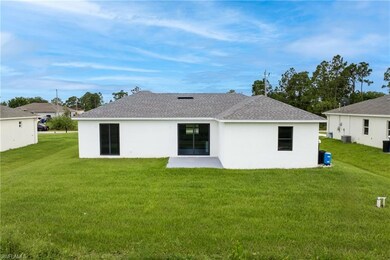 Back of property with a yard, stucco siding, and roof with shingles