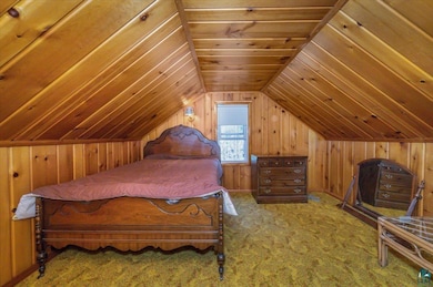 Bedroom featuring wood walls, lofted ceiling, carpet flooring, and wood ceiling