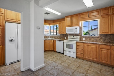 Kitchen with white appliances, a sink, tasteful ba