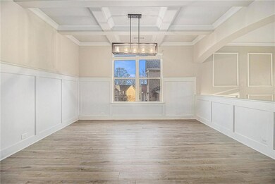 Unfurnished dining area featuring a decorative wall, a chandelier, wood finished floors, beamed ceiling, and coffered ceiling