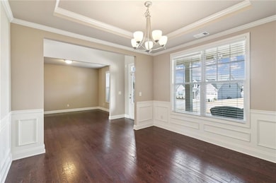 Empty room featuring a tray ceiling, visible vents