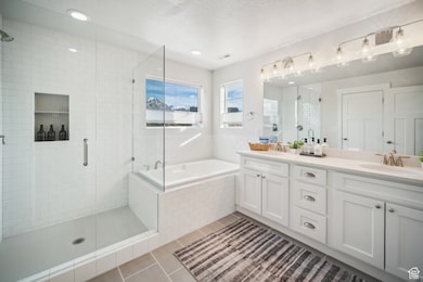 Bathroom featuring tile patterned floors, double vanity, a garden tub, a shower stall, and a textured ceiling