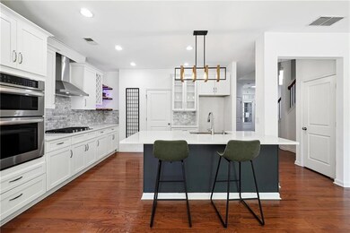 Kitchen with wall chimney range hood, a sink, stai