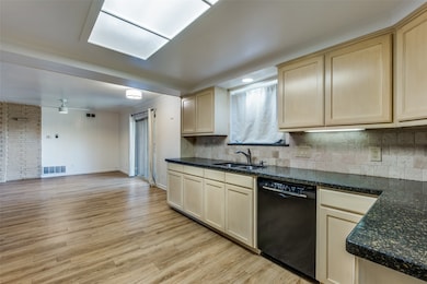 Kitchen with black dishwasher, light wood finished floors, decorative backsplash, open floor plan, and ceiling fan