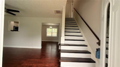 Stairway with ceiling fan, wood finished floors, baseboards, and a textured ceiling
