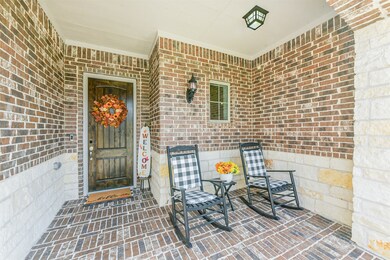 Rich wood front door framed by brick flooring and stylish lighting. The entryway sets the tone for the home’s inviting interior.