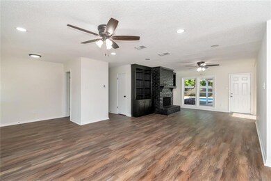 Living room featuring ceiling fan, baseboards, dark wood-style flooring, a textured ceiling, and a fireplace
